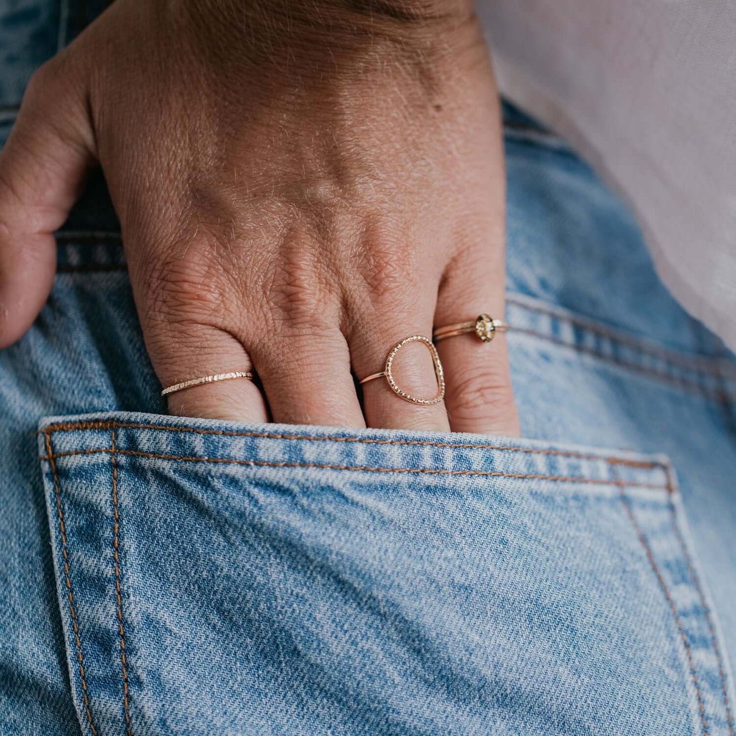 Hand with gold rings on a blue denim background