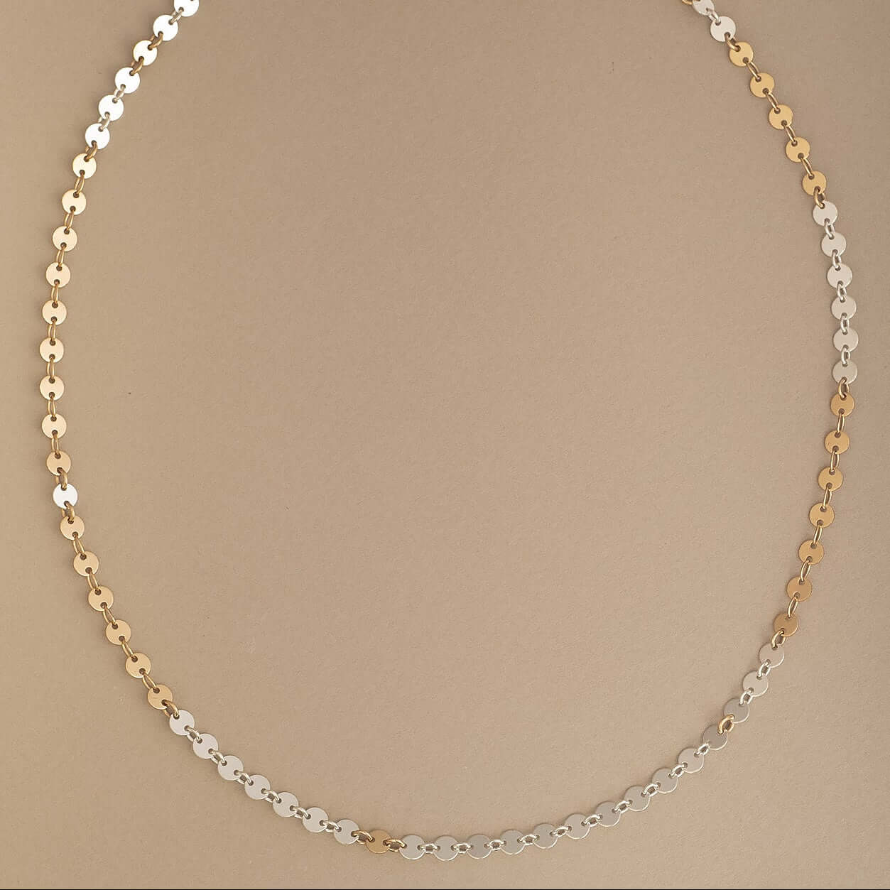 Necklace with gold and silver beads on a beige background