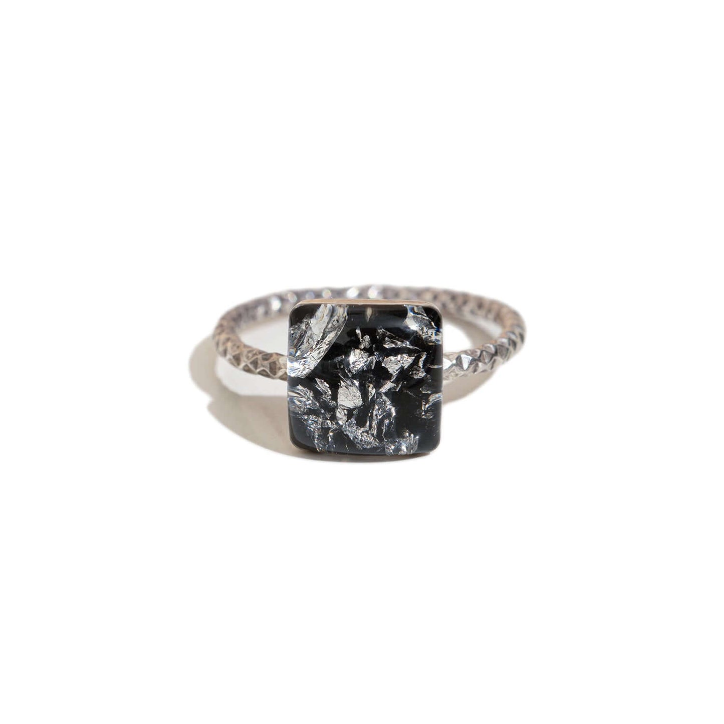 Silver ring with a black and silver square stone on a white background