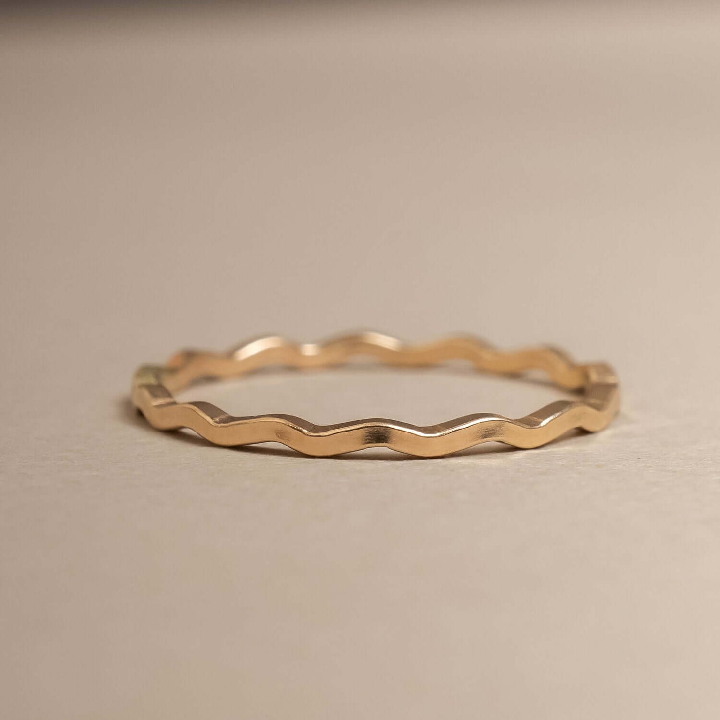 Gold wavy ring on a beige background