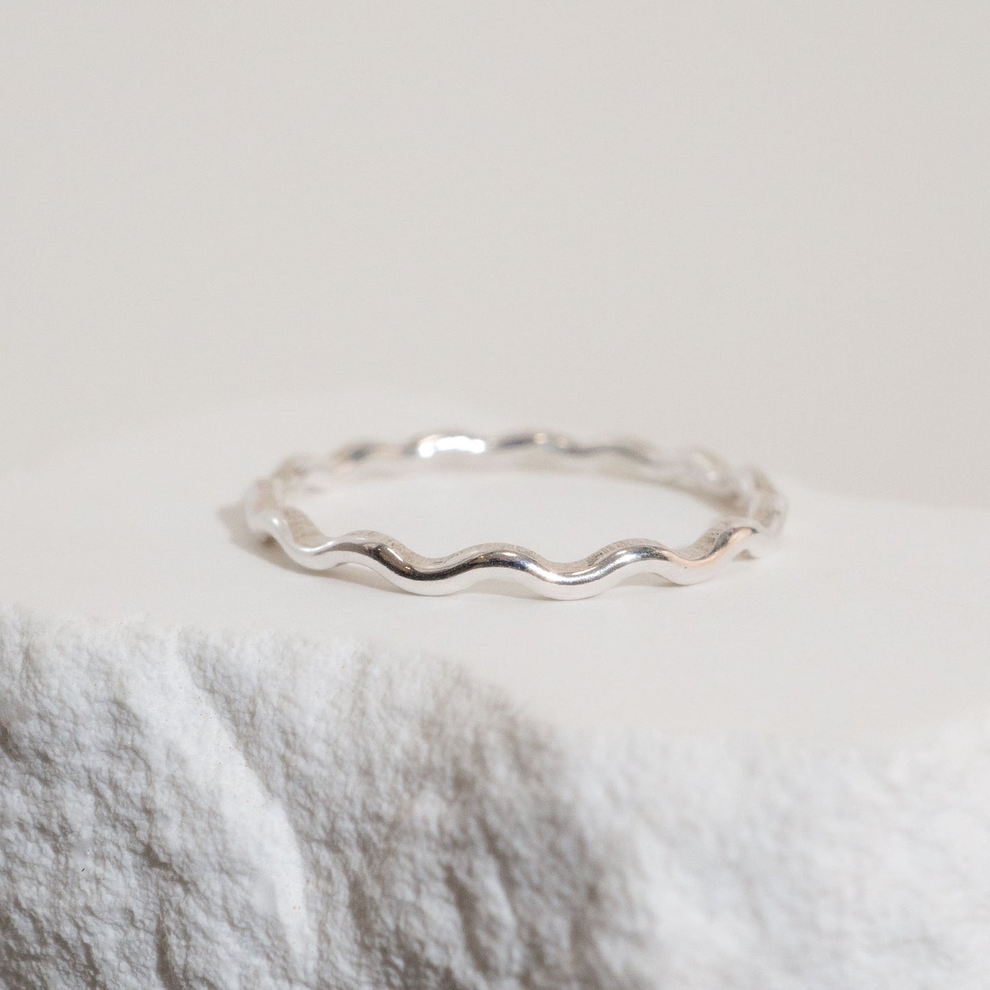 Silver wavy ring on a textured white surface