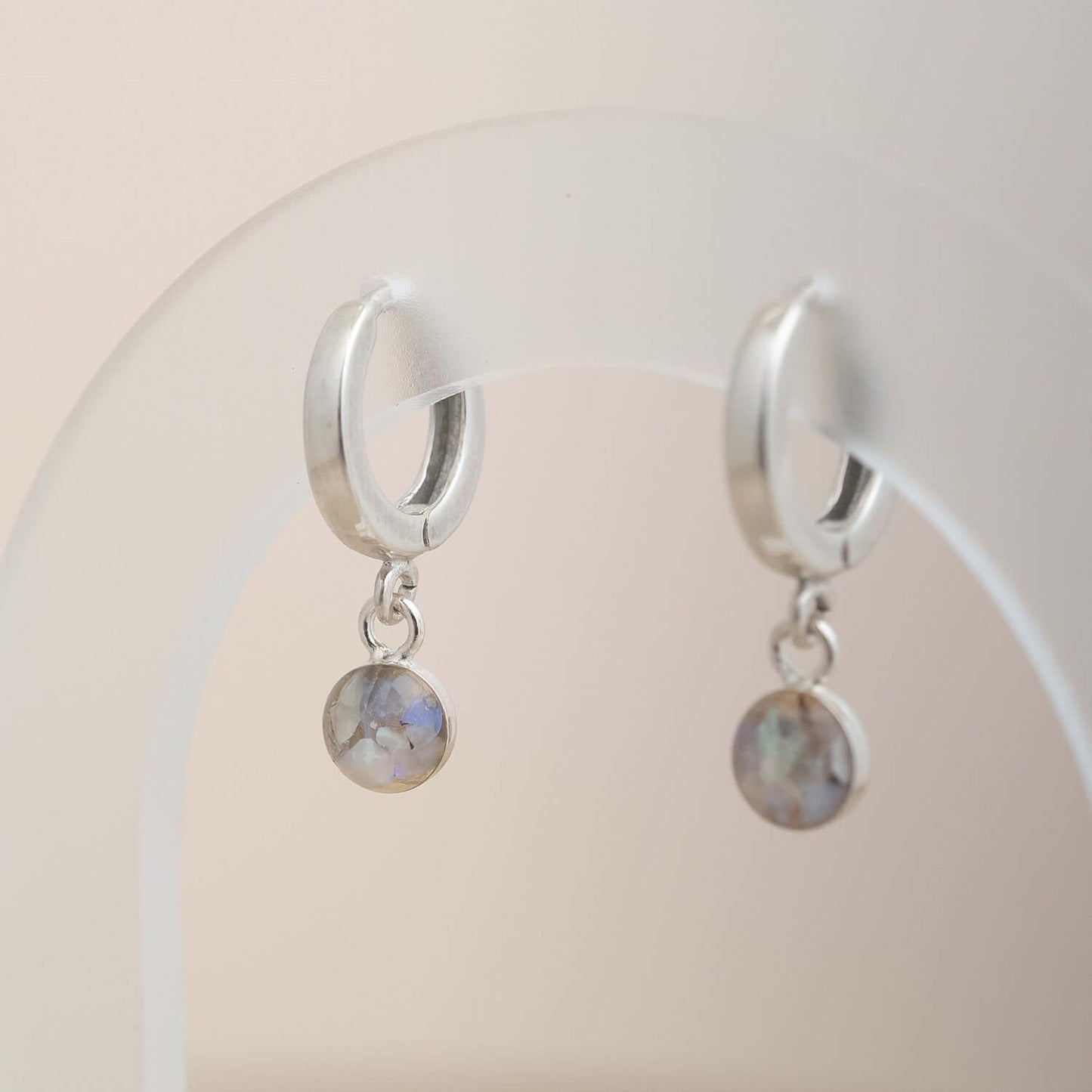 Silver hoop earrings with round gemstones on a neutral background