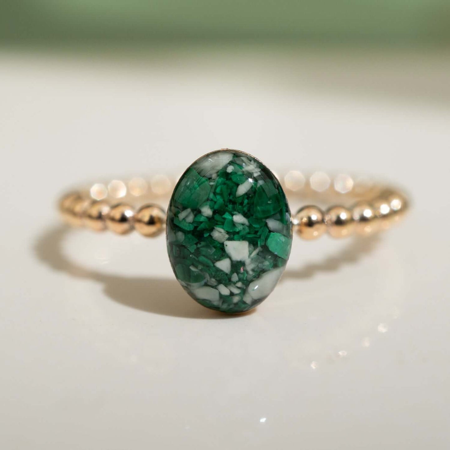 Ring with a green stone and gold band on a light background