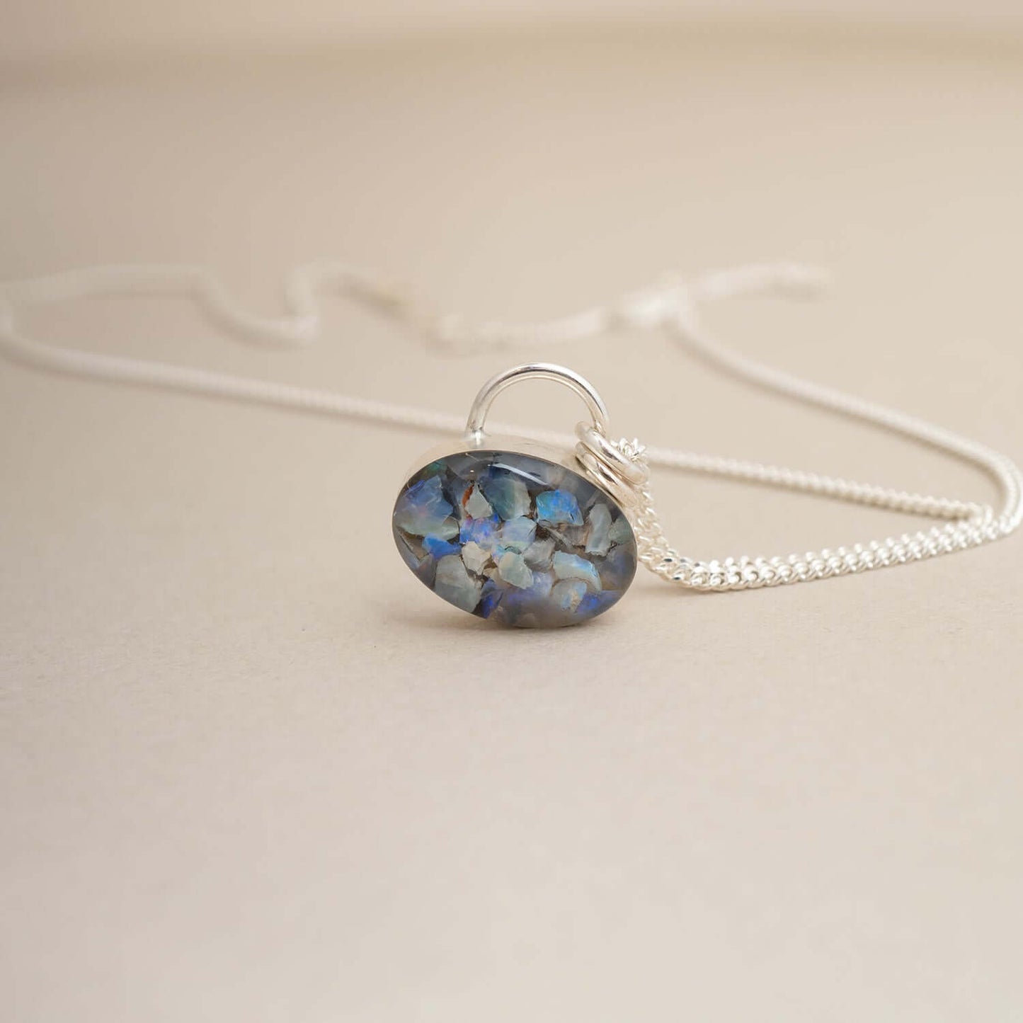 Necklace with a pendant featuring blue and silver design on a beige background