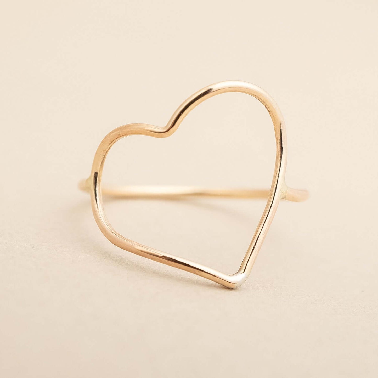 Gold heart-shaped ring on a beige background