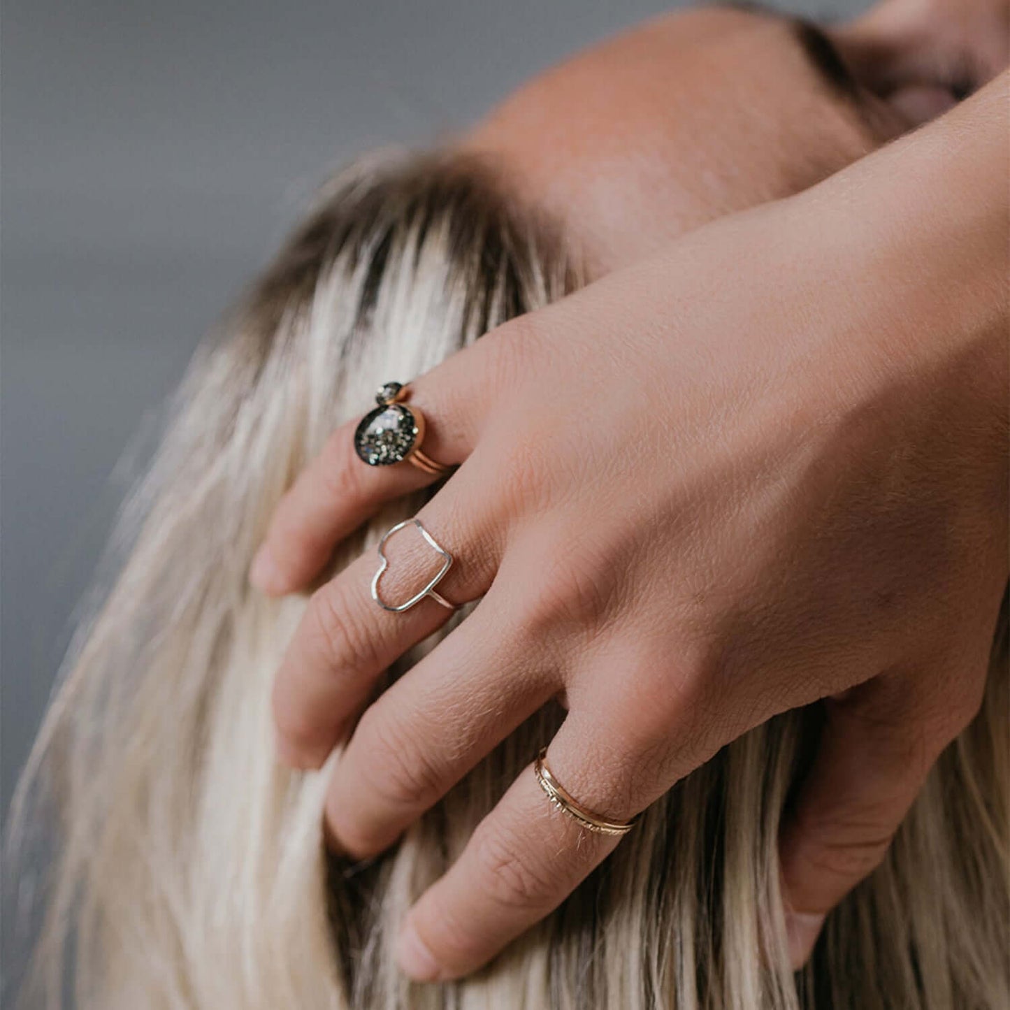 Close-up of a hand with multiple rings on a blurred background