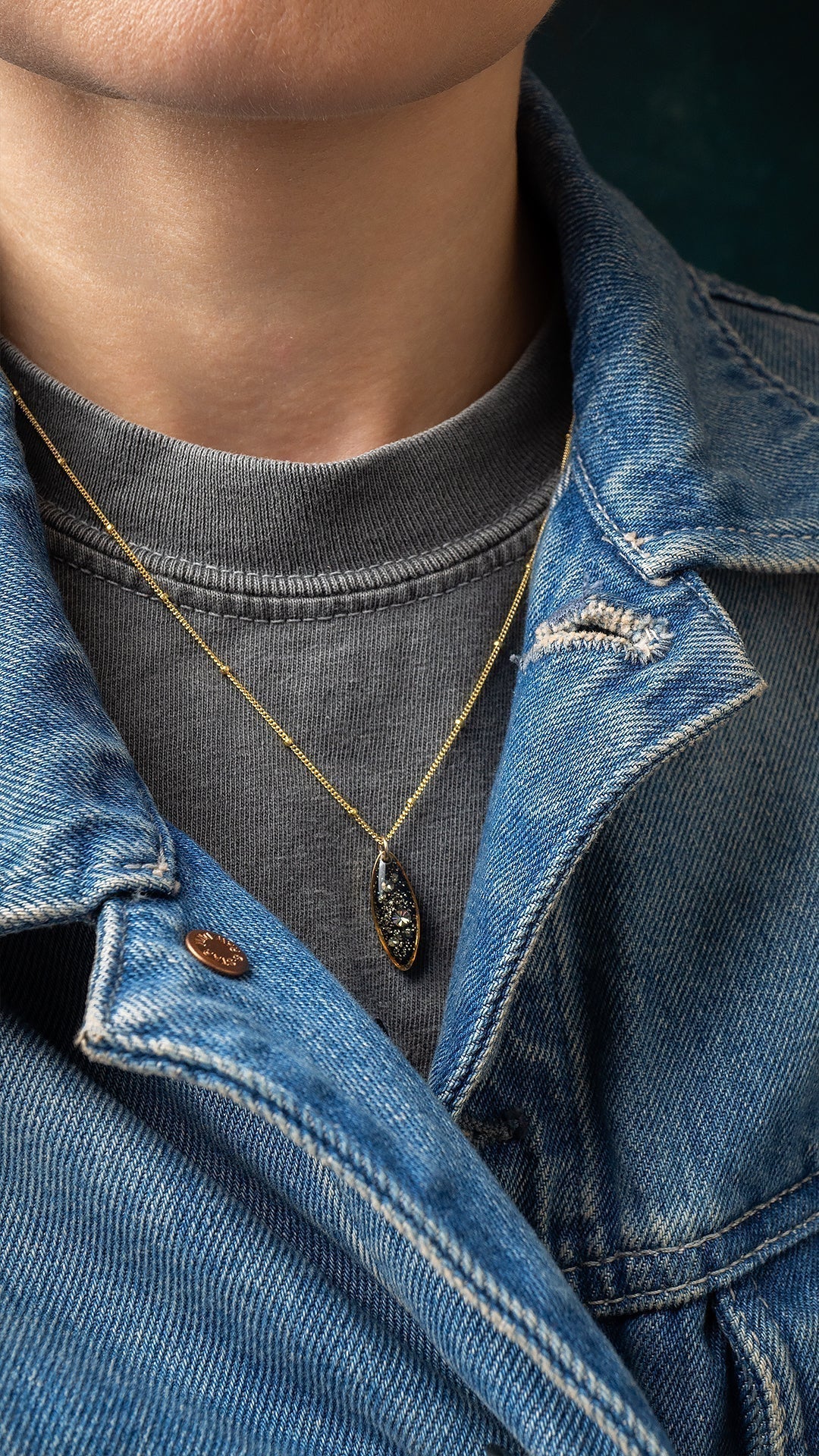 Gold pendant necklace with gemstone resting on neckline, Kate Koel handmade jewelry