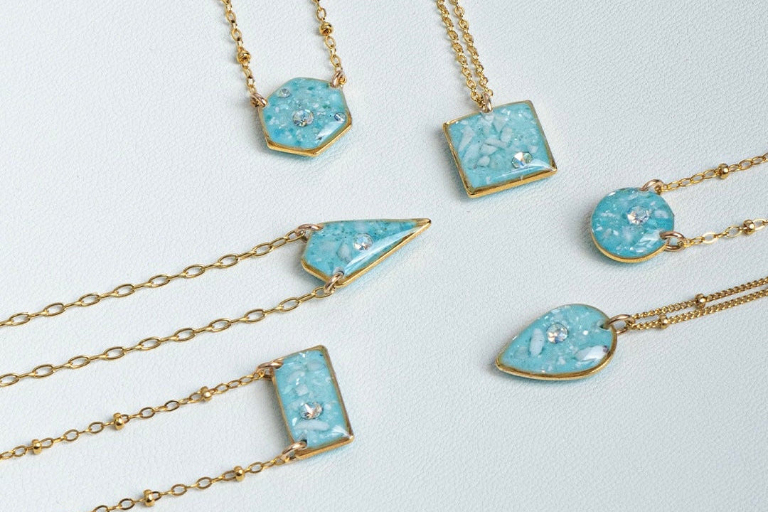 Set of gold necklaces with blue gemstones on a white surface