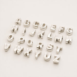 A set of polished silver alphabet beads spelling out the letters A through Z, arranged in rows on a clean white background.
