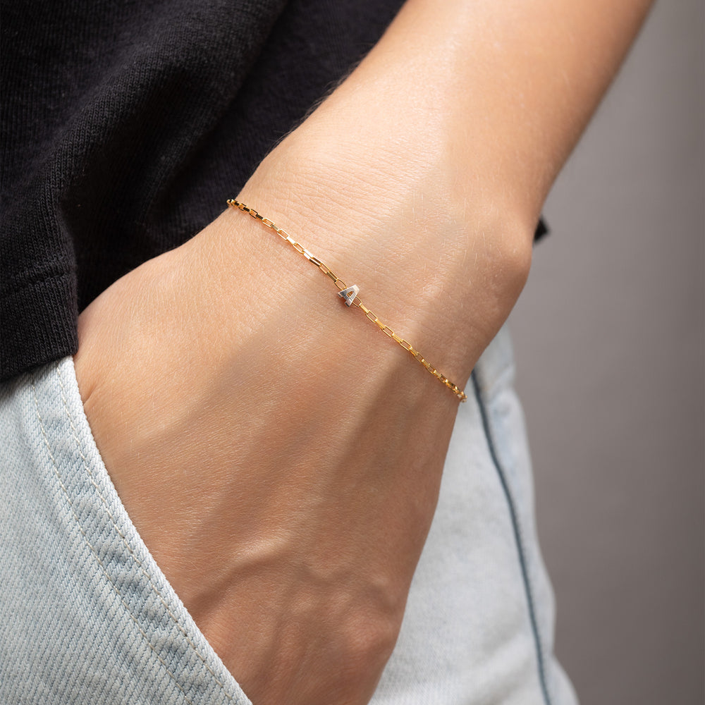 Two gold-tone chain necklaces laid on a light neutral background, each paired with a row of silver-tone initial charms spelling out names.