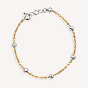 A delicate gold chain bracelet with five evenly spaced polished silver-tone spherical beads and a matching clasp, displayed on a clean off-white background.