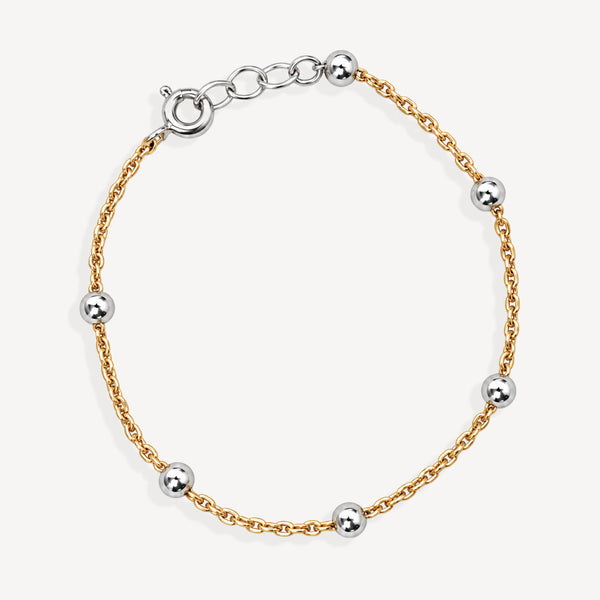 A delicate gold chain bracelet with five evenly spaced polished silver-tone spherical beads and a matching clasp, displayed on a clean off-white background.