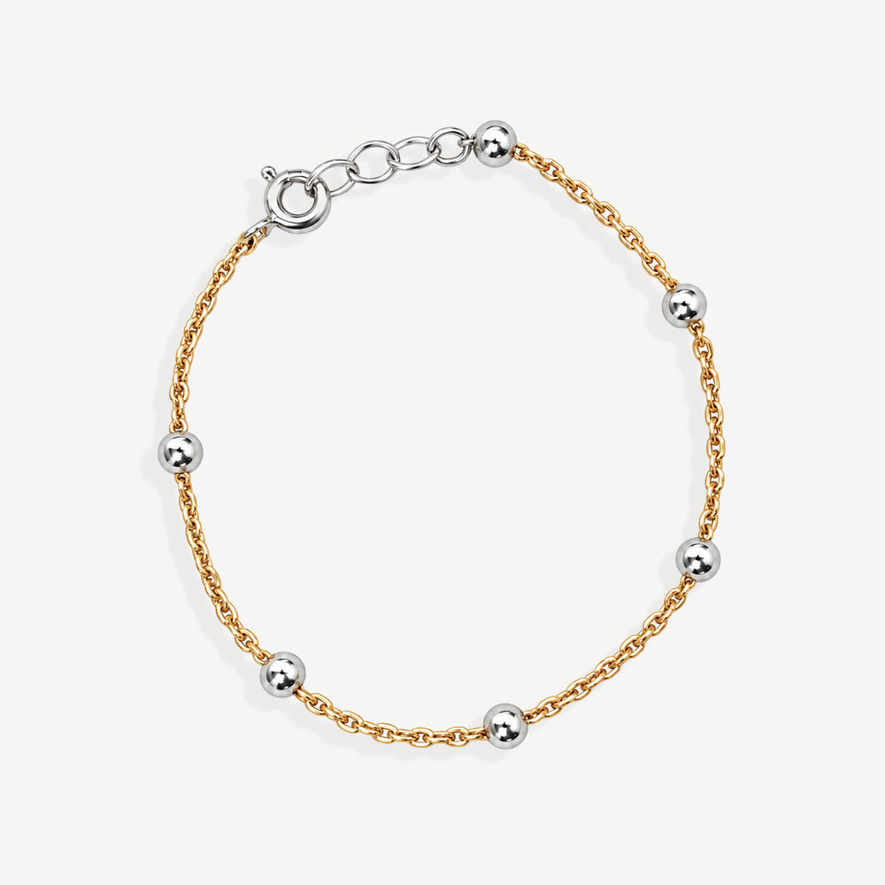 A delicate gold chain bracelet with evenly spaced polished silver ball accents and a lobster clasp, shown on a clean off-white background.