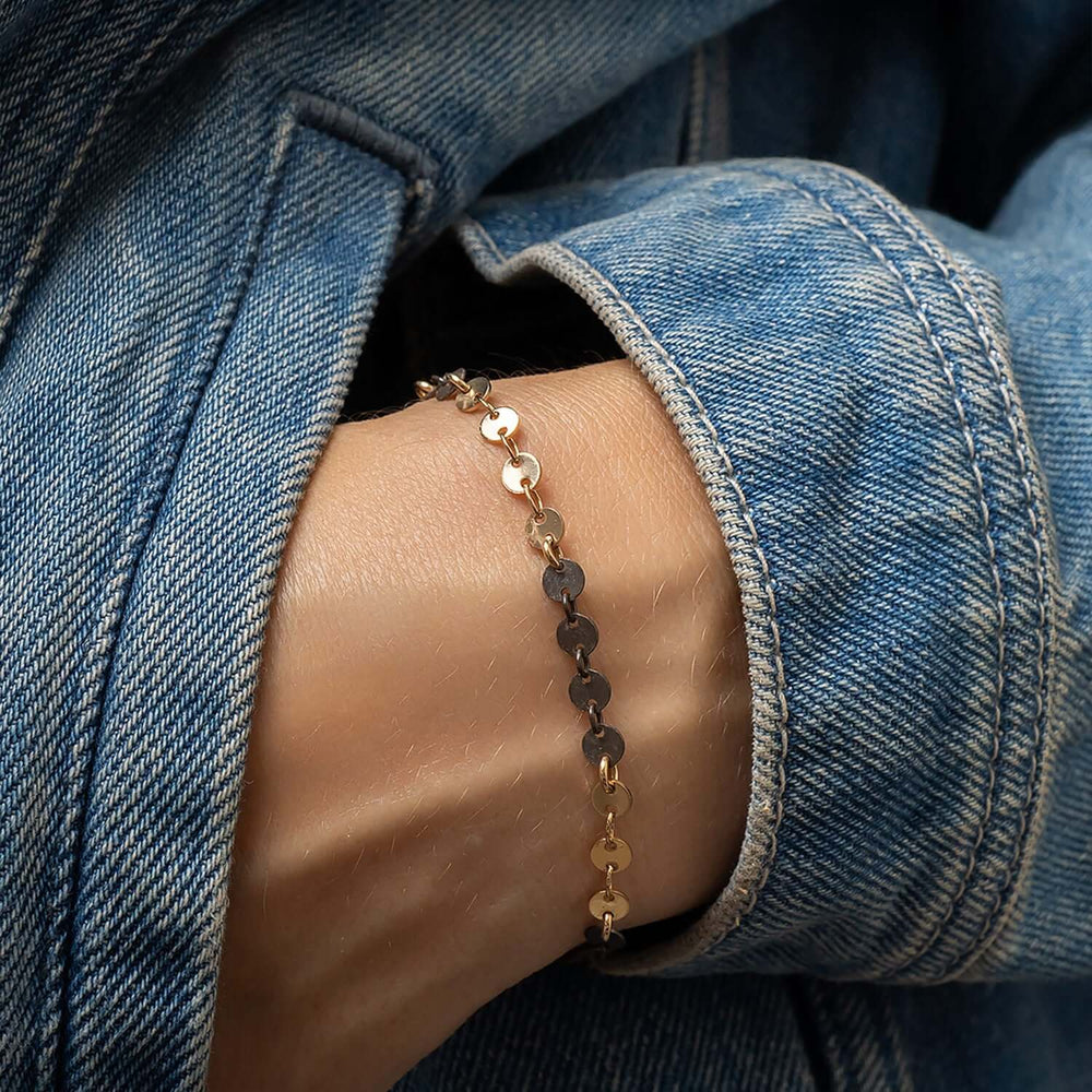 
                      
                        Gold and silver beaded bracelet on a wrist with denim background
                      
                    