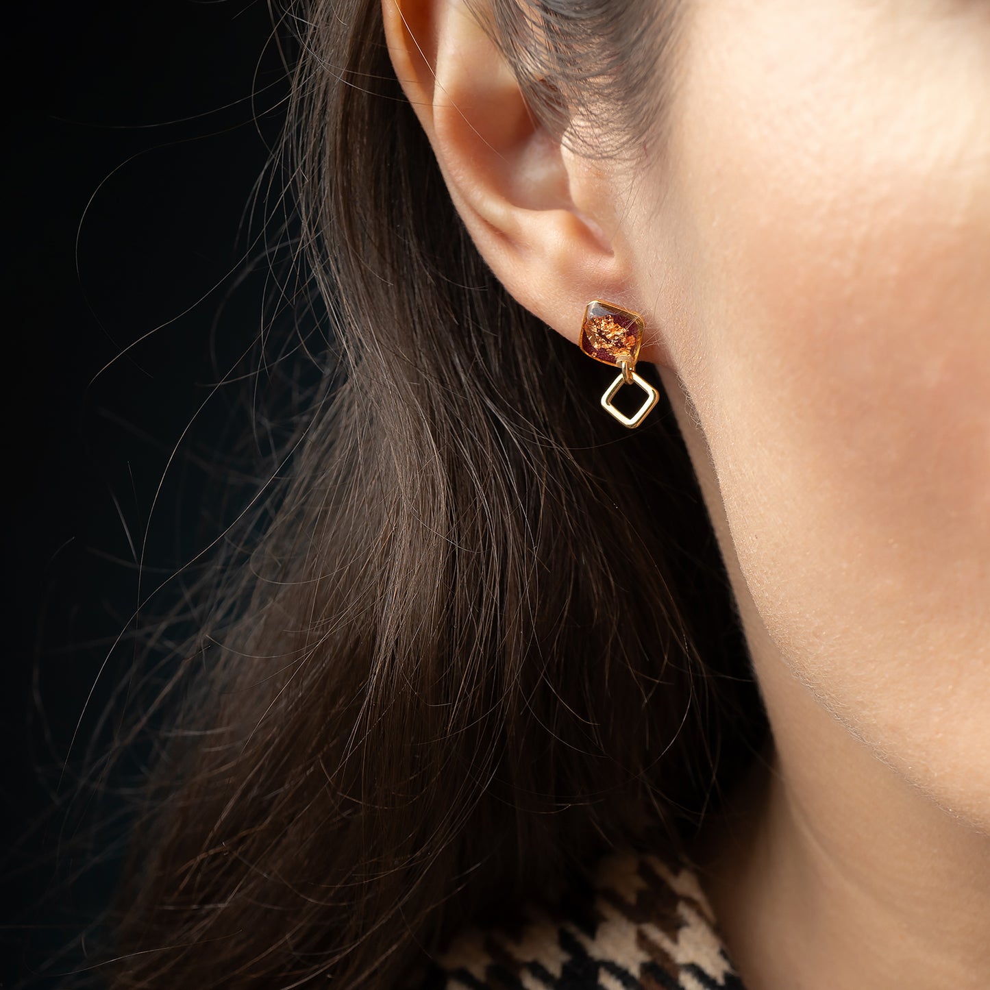 Close-up of a person wearing a pair of earrings with a dark background
