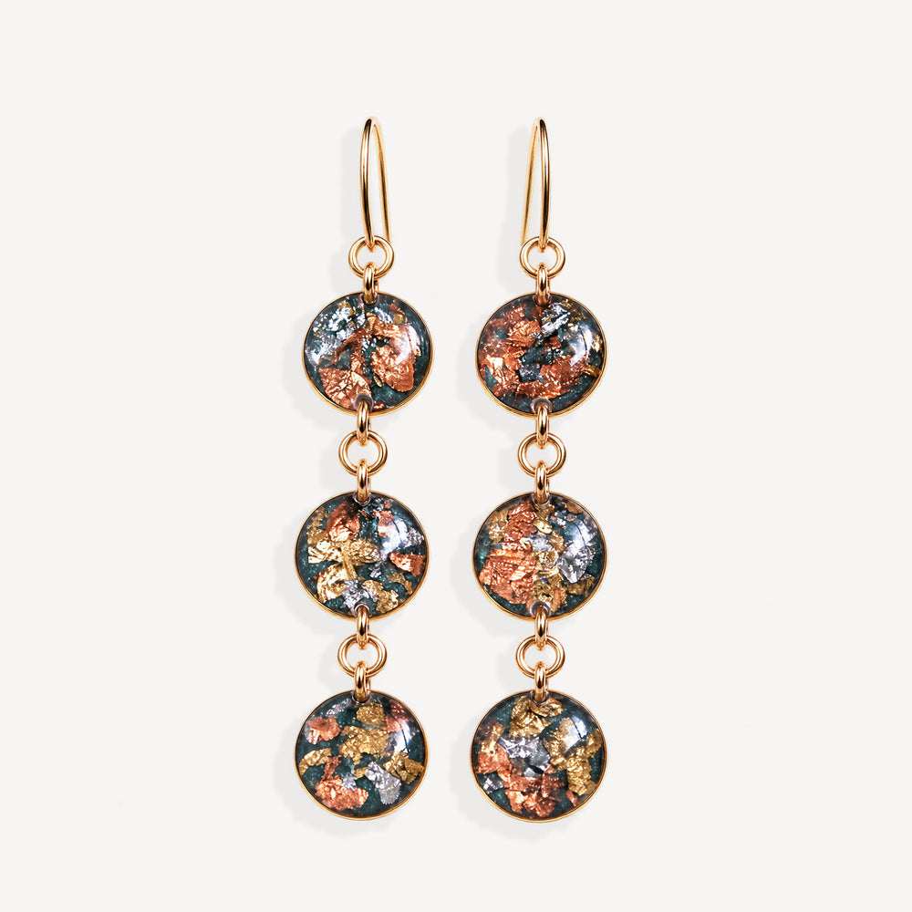 A pair of gold-tone dangle earrings with three circular glass disc charms each featuring a colorful metallic foil pattern of copper, gold, and silver on a dark background, set against a plain off-white background.