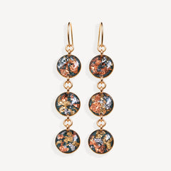 A pair of gold-tone dangle earrings with three circular glass disc charms each featuring a colorful metallic foil pattern of copper, gold, and silver on a dark background, set against a plain off-white background.