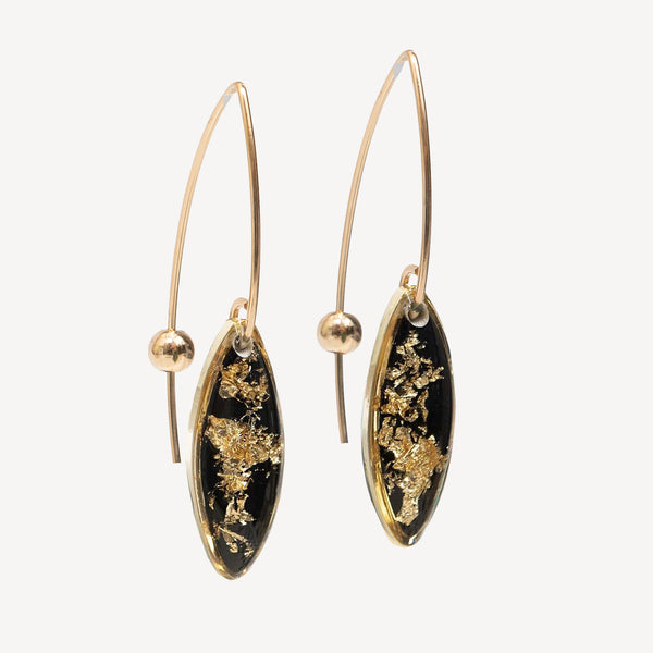 A pair of gold hoop earrings with marquise-shaped black dangles featuring embedded gold leaf, shown against a light gray background.