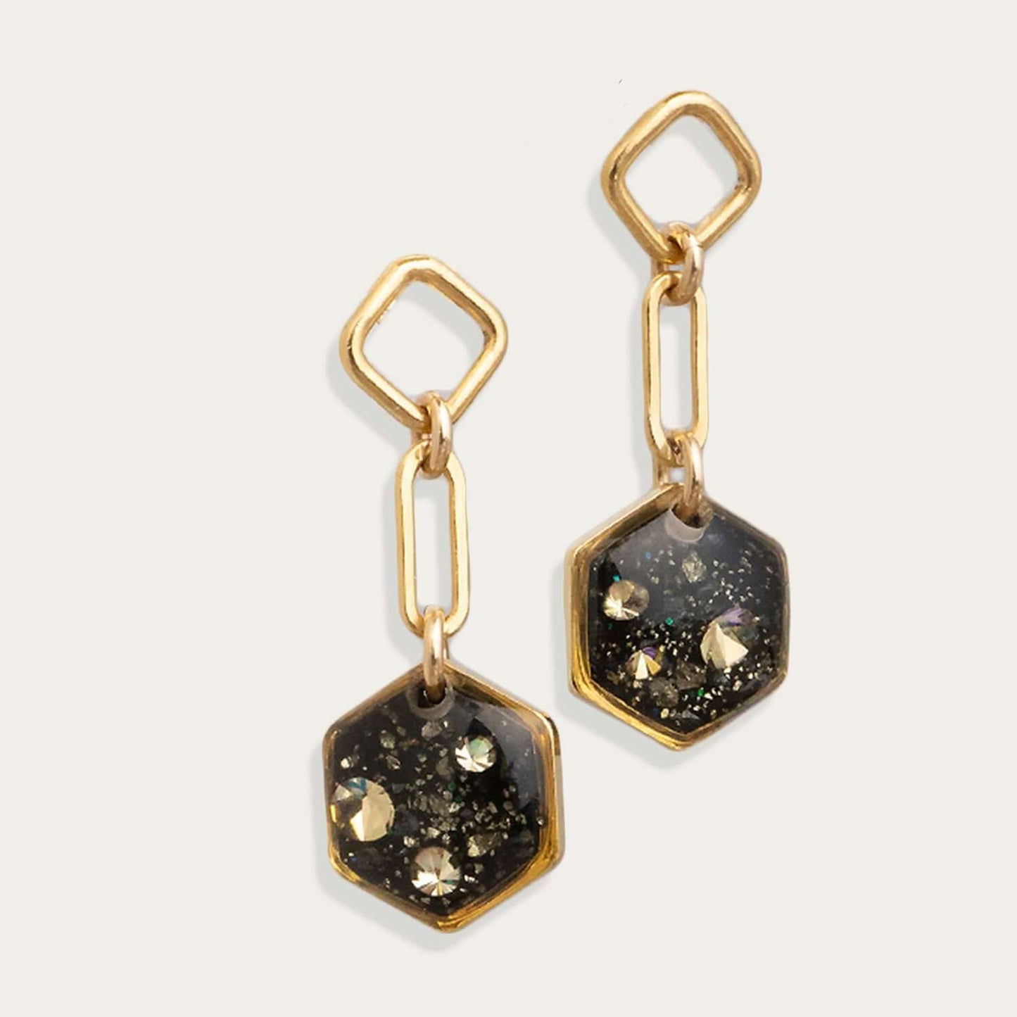 Gold and black hexagonal earrings on a light gray background