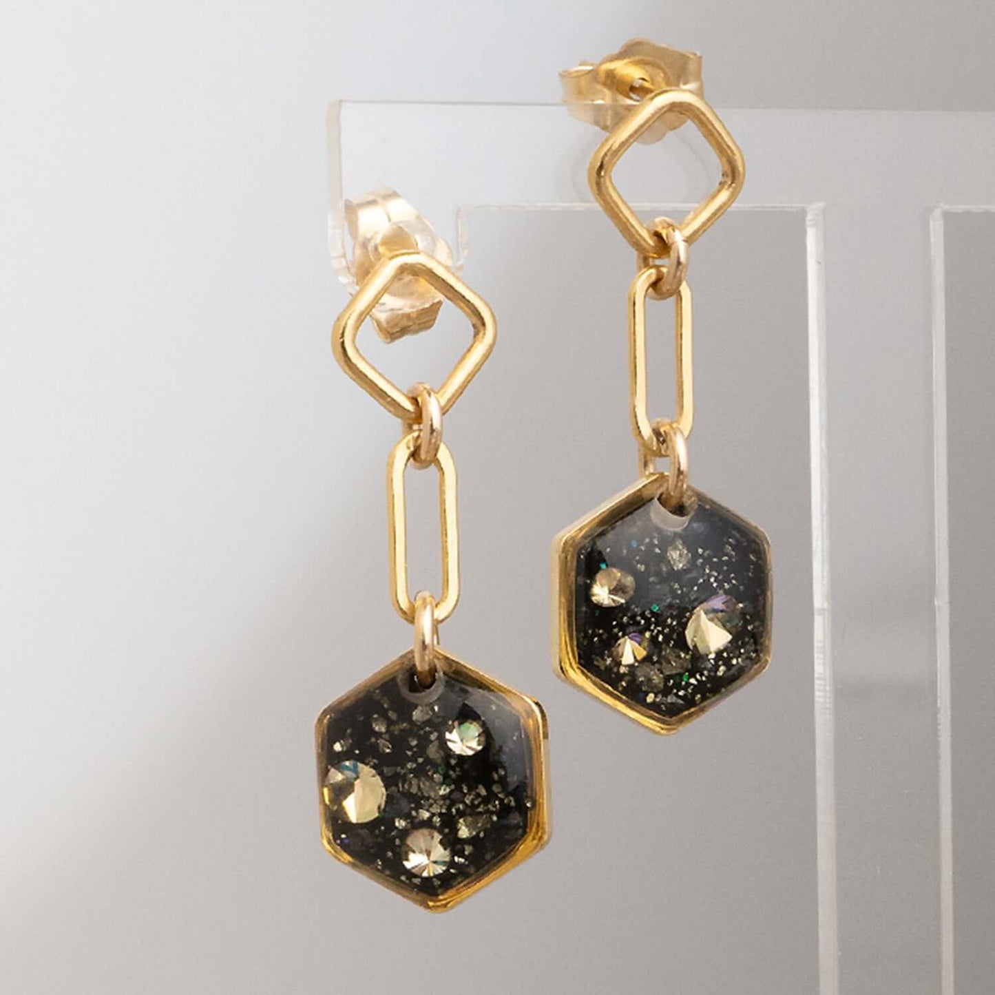 Gold earrings with black and gold gemstones on a light gray background