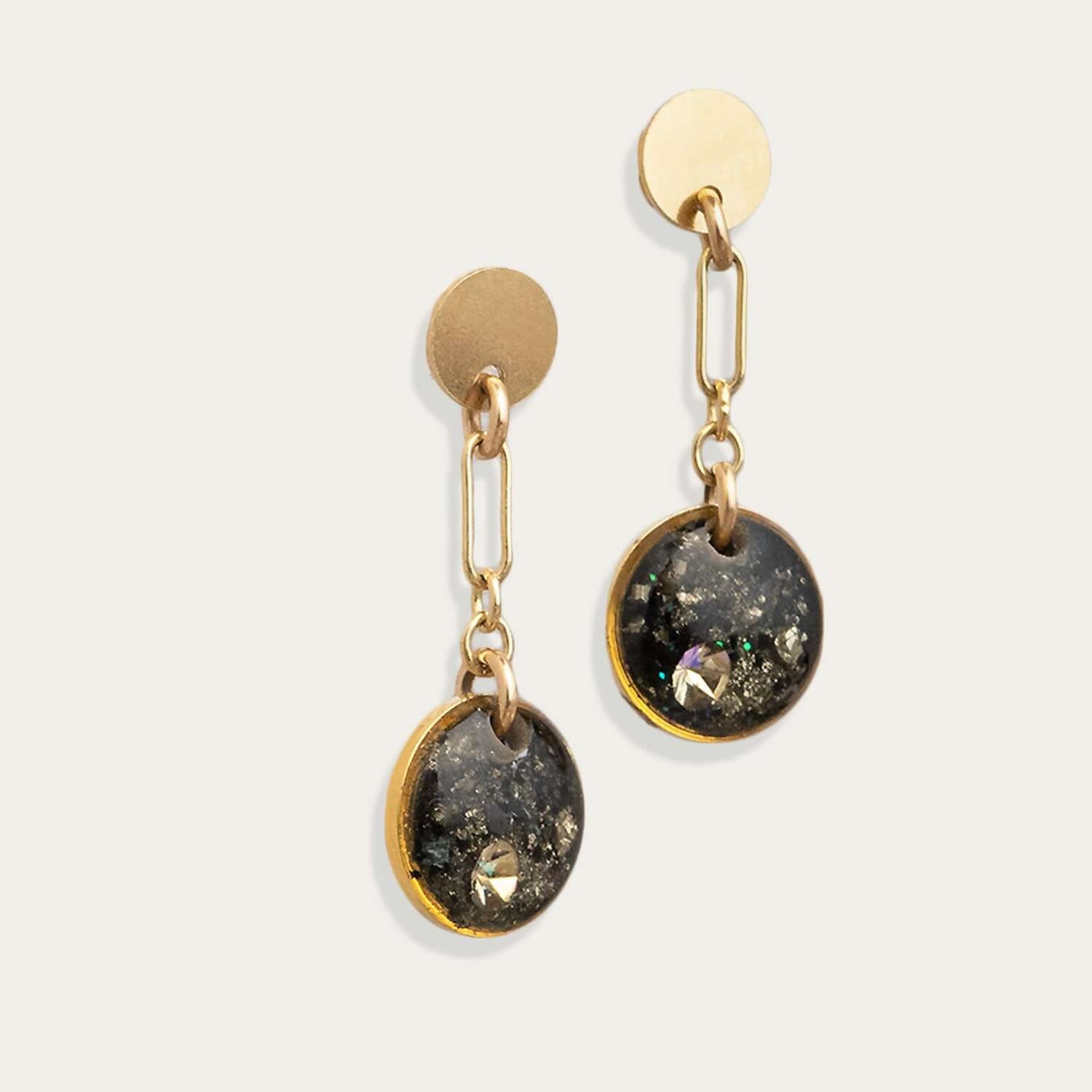 Gold and black earrings on a light gray background