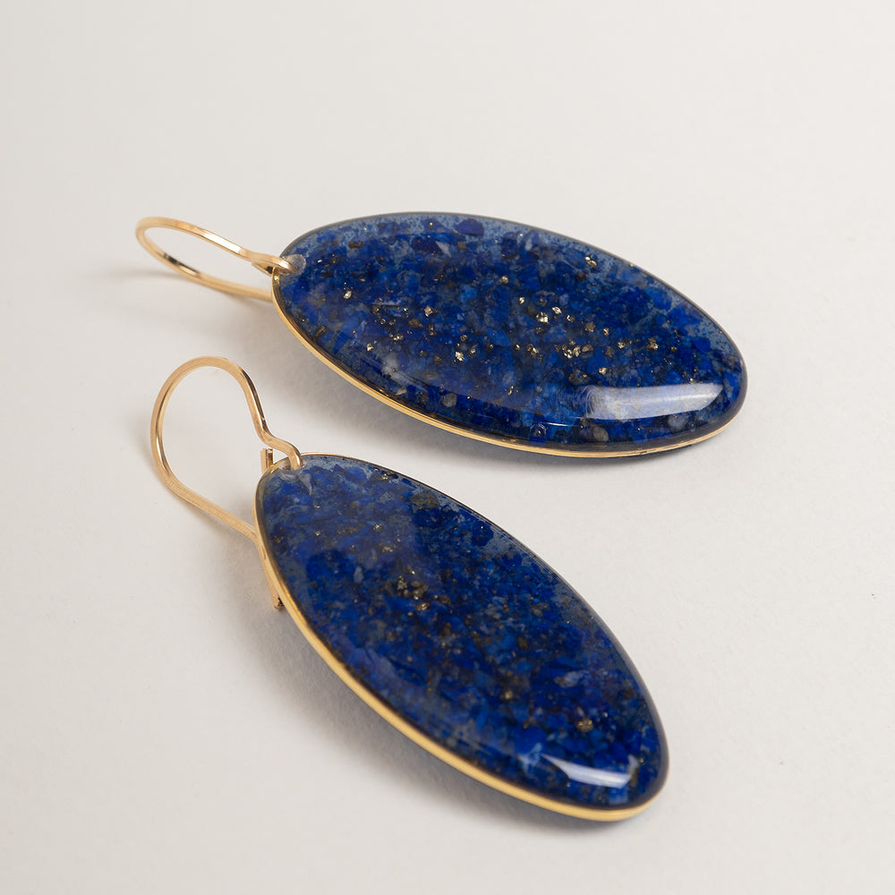 A pair of gold-tone drop earrings with oval blue agate pendants, shown against a plain off-white background.