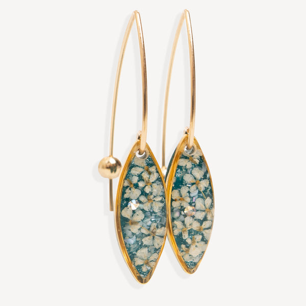 A pair of gold drop earrings with marquise-shaped teal and white floral resin inlays, shown against a light gray background.