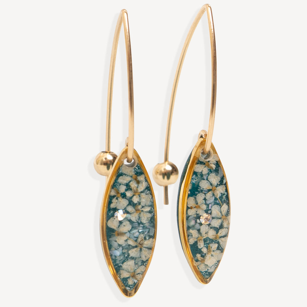 A pair of gold-tone dangle earrings with marquise-shaped turquoise and white floral resin inlays, shown against a light gray background.