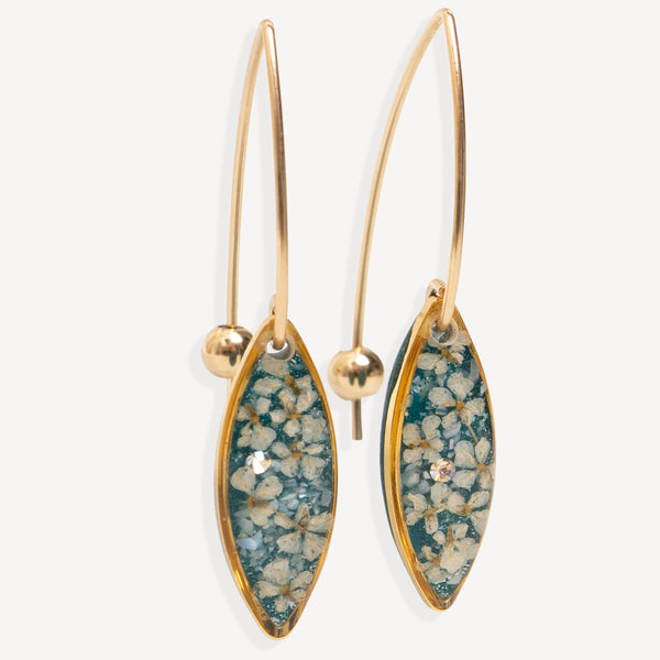 A pair of gold-tone dangle earrings with marquise-shaped turquoise and white floral resin inlays, shown against a light gray background.
