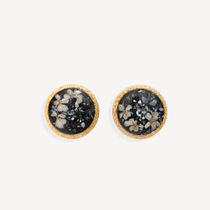 A pair of round gold-tone stud earrings featuring a black druzy stone inlay with white and gray crystalline patterns, set against a clean off-white background.
