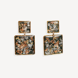 A pair of square drop earrings with textured, metallic inlay details in copper, silver, and dark green tones, set in a gold-tone frame on a light gray background.