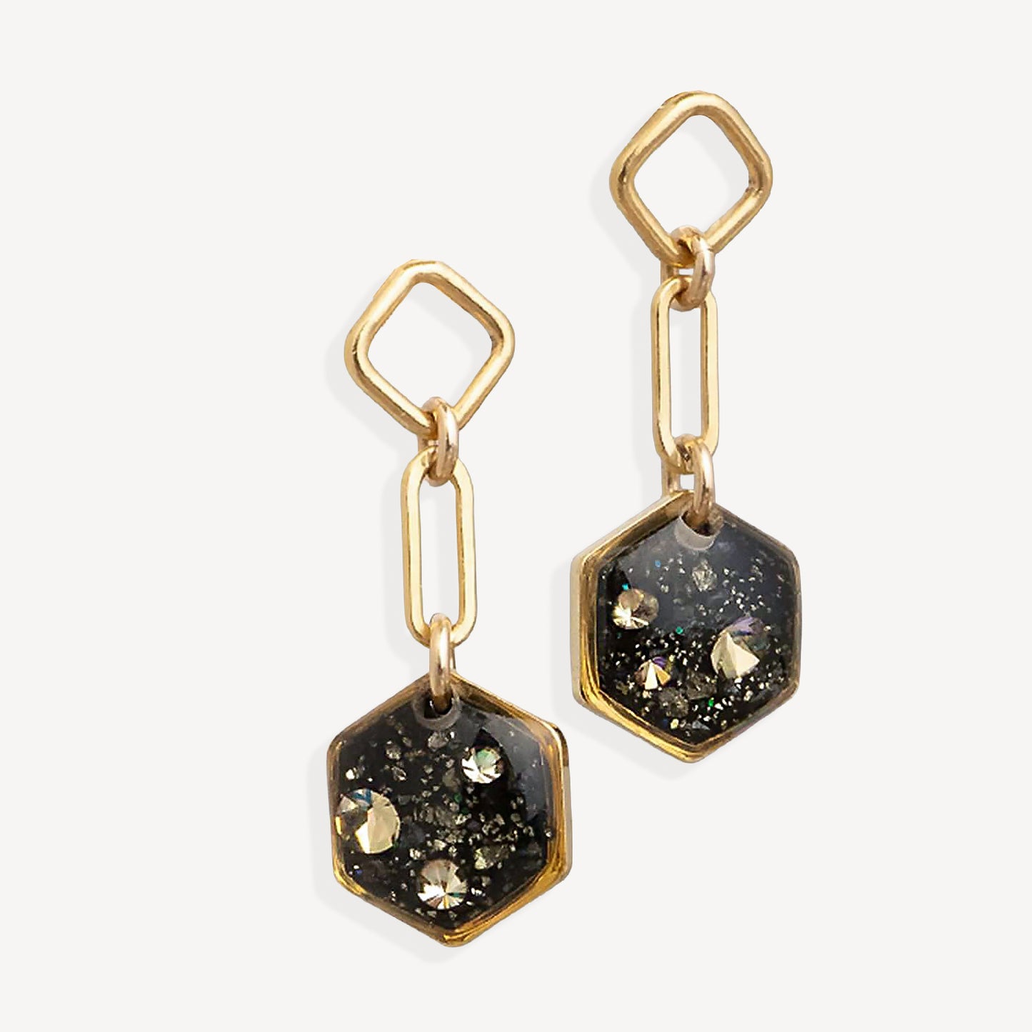 Gold and black hexagonal earrings on a white background