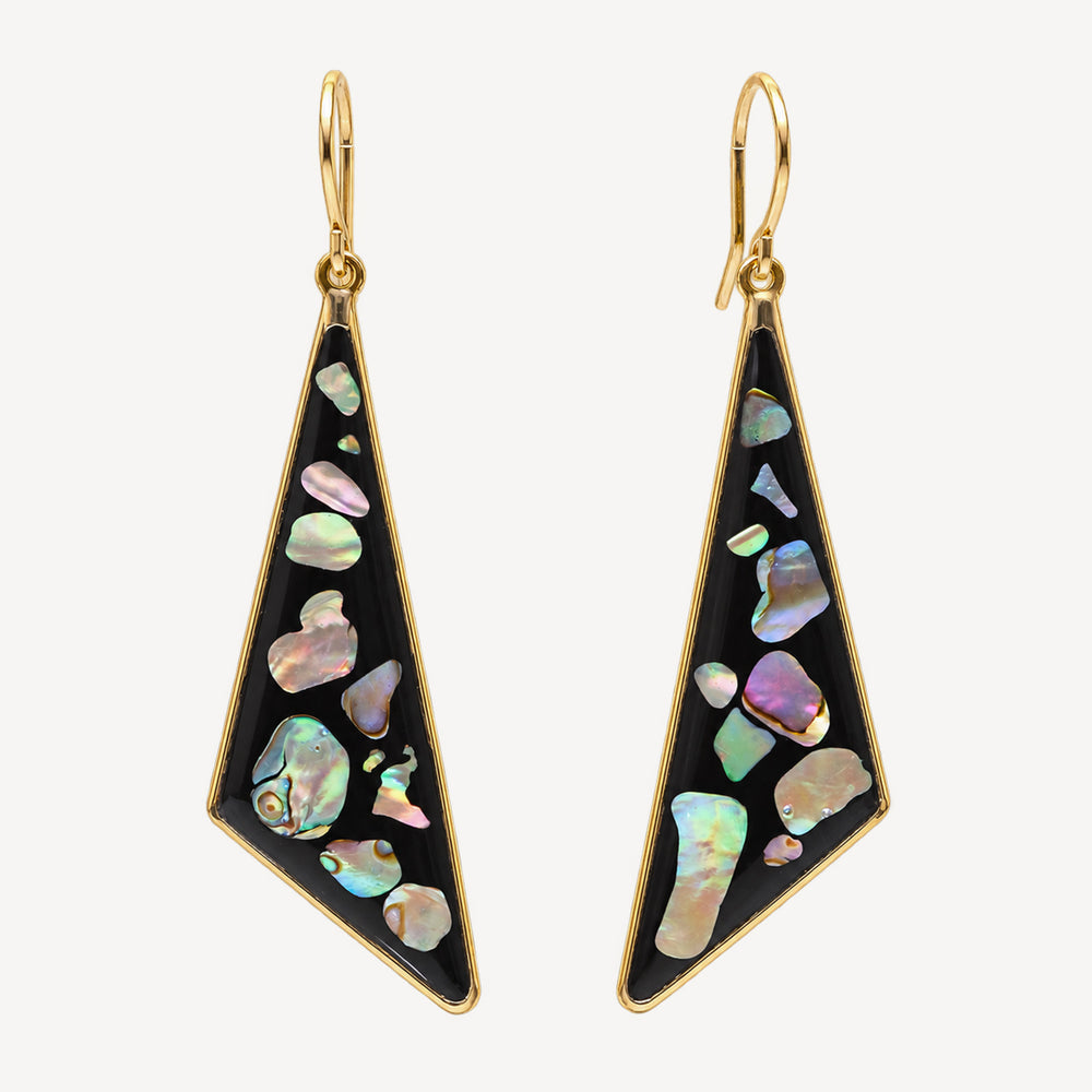 A pair of gold-tone drop earrings with irregular iridescent abalone shell inlays on a black background, shown against a light off-white studio background.
