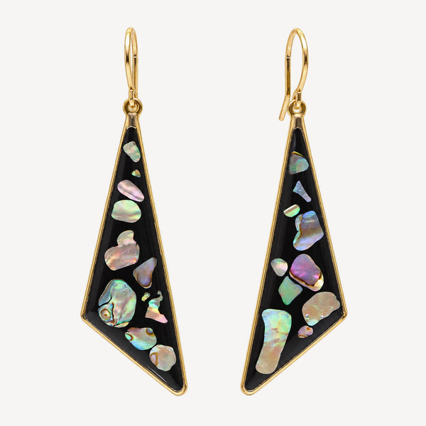 A pair of gold-tone drop earrings with irregular iridescent abalone shell inlays on a black background, shown against a light off-white studio background.