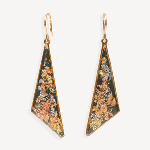 A pair of gold-tone geometric drop earrings with triangular pendants featuring a dark green background and a textured, metallic orange, gold, and silver inlay, shown against a plain off-white background.