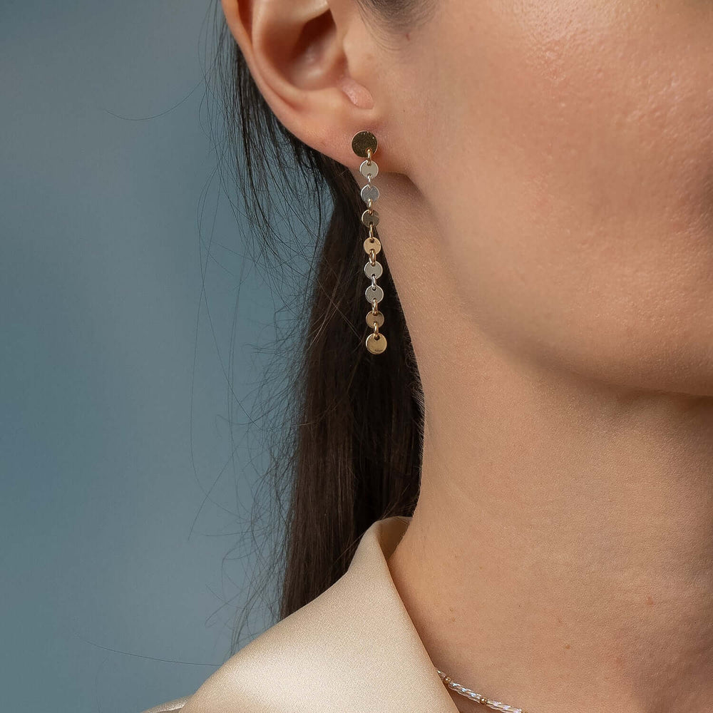 
                      
                        Close-up of an ear wearing a dangling earring with a blue background
                      
                    