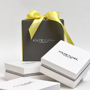 Kate Koel jewelry boxes with a yellow ribbon on a white background