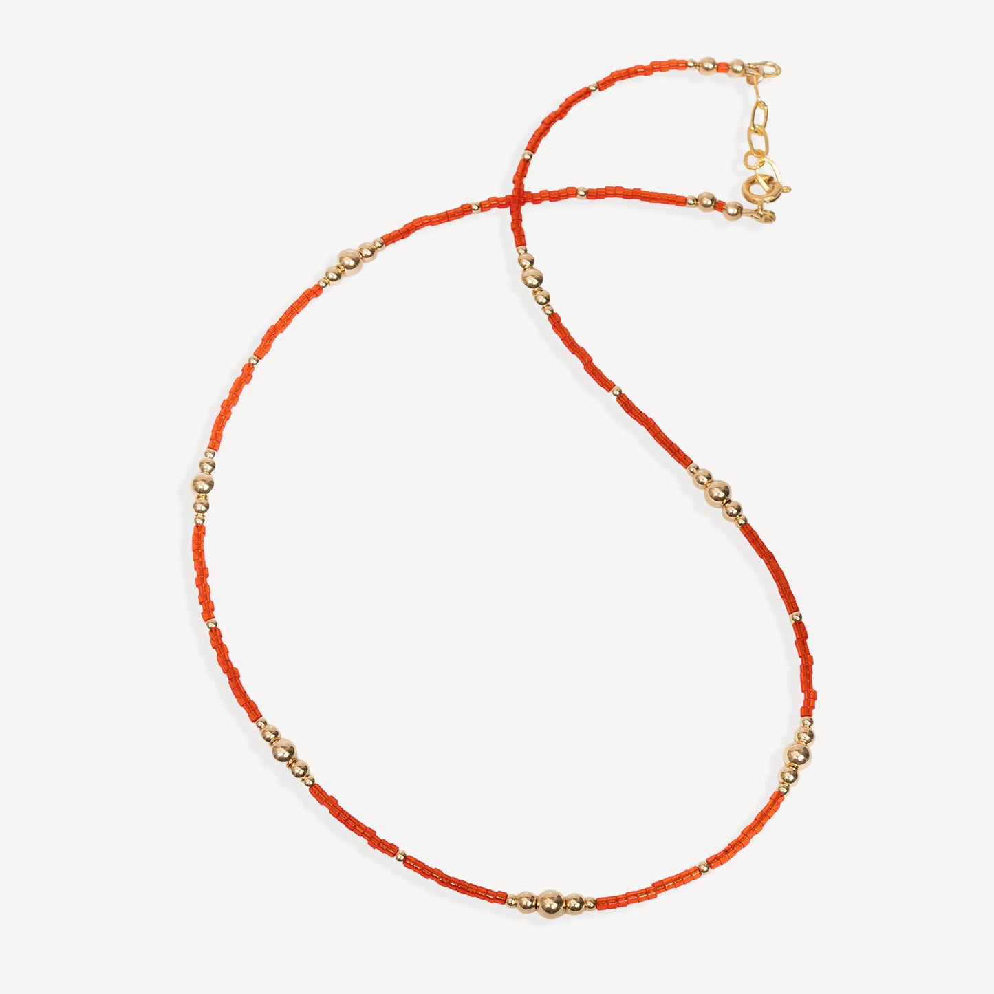 Necklace with orange beads and gold accents on a white background