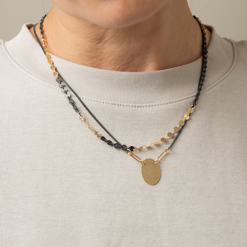 
                      
                        Necklace with gold and black beads on a plain background
                      
                    