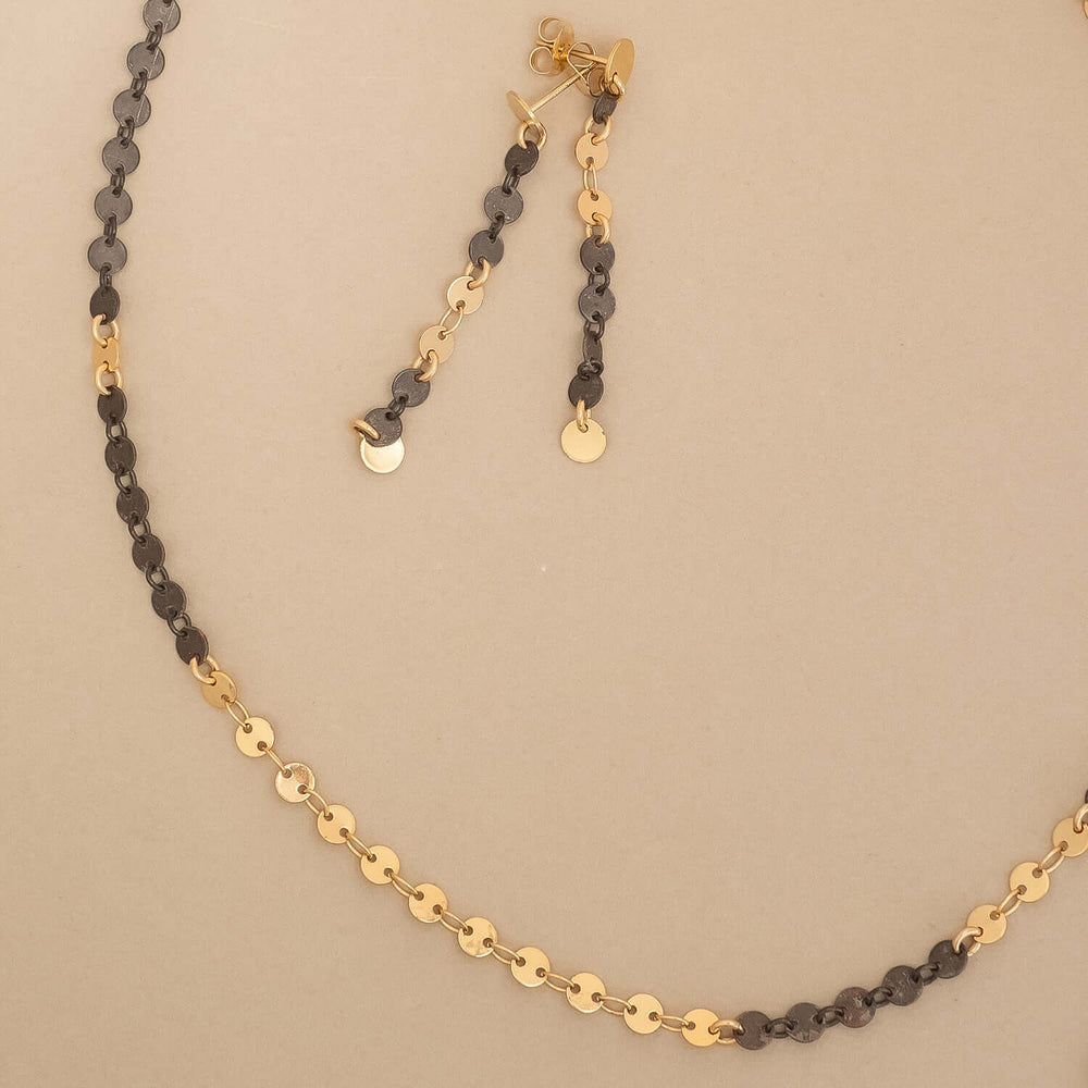 
                      
                        Gold and black beaded necklace on a beige background
                      
                    