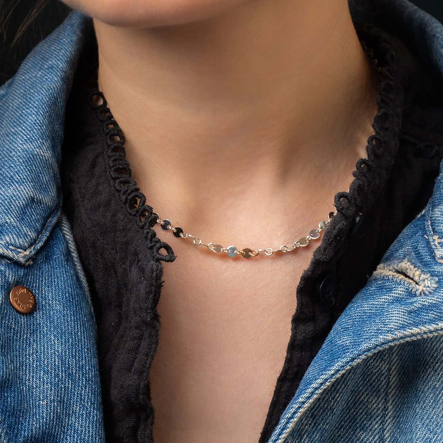 Necklace with heart-shaped pendants worn by a person in a denim jacket.