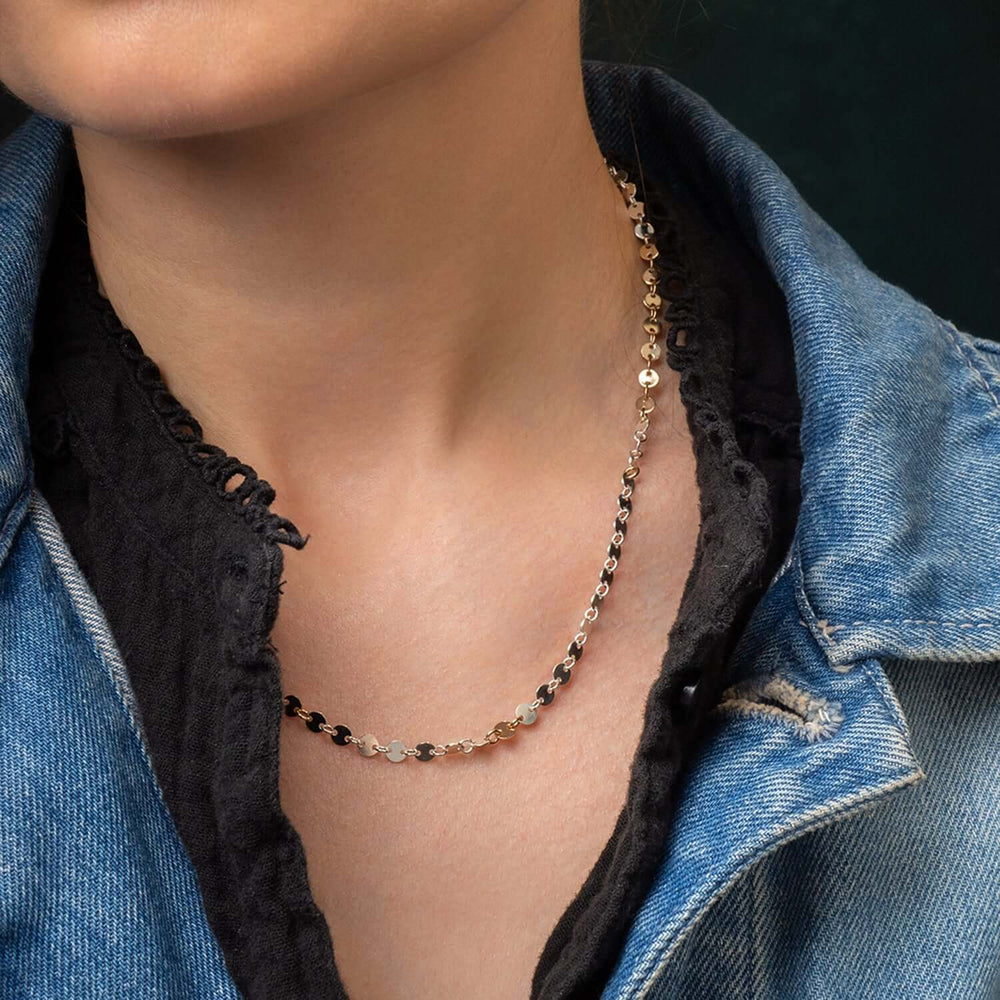 
                      
                        Person wearing a delicate necklace with a dark background
                      
                    