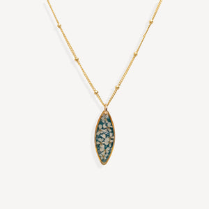 A gold chain necklace with a marquise-shaped pendant featuring a teal blue background and white floral details, shown against a light gray background.