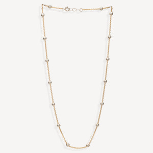 A delicate gold chain necklace featuring evenly spaced, polished metallic beads, displayed against a clean, off-white background.