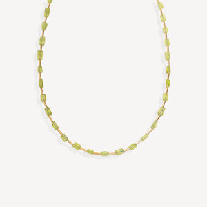 A delicate necklace made of small, faceted light green beads strung on a thin gold-tone chain, displayed against a clean, off-white background.