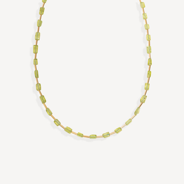 A delicate necklace made of small, faceted light green beads strung on a thin gold-tone chain, displayed against a clean, off-white background.
