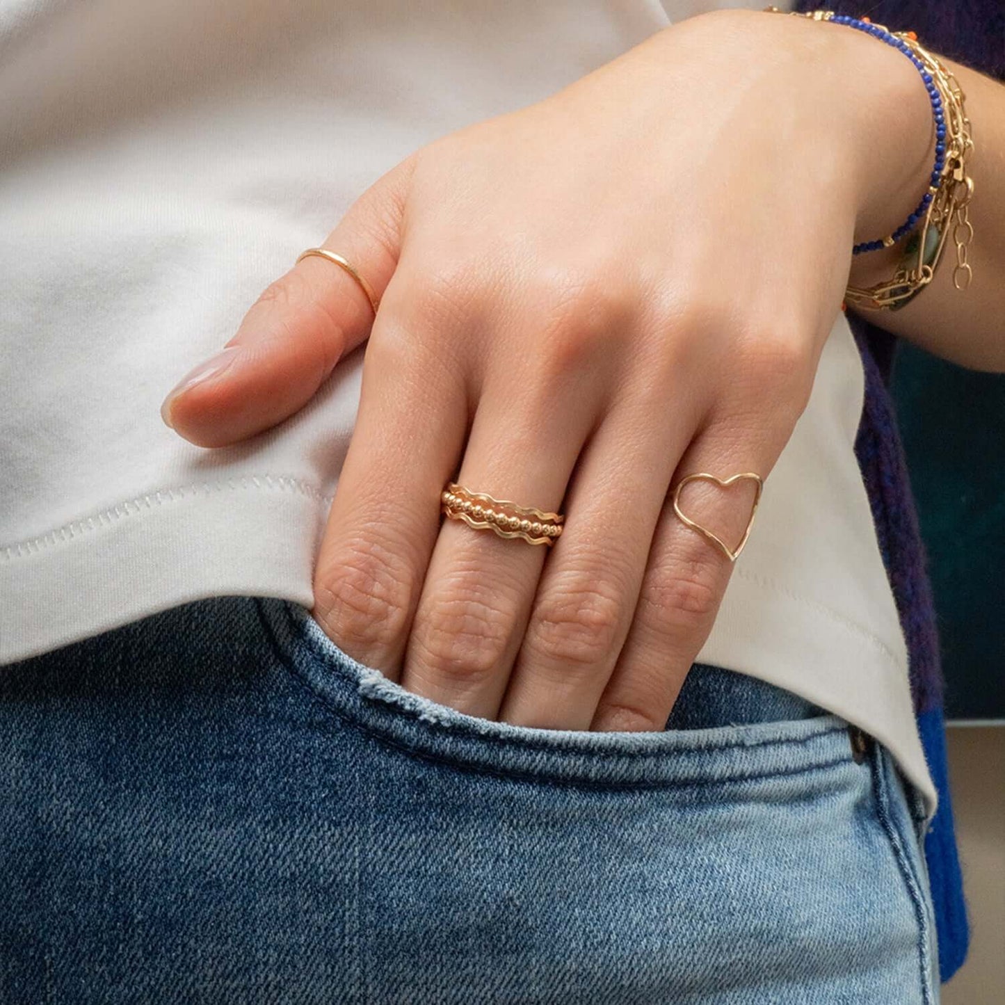 Close-up of a hand wearing gold rings with a blurred background