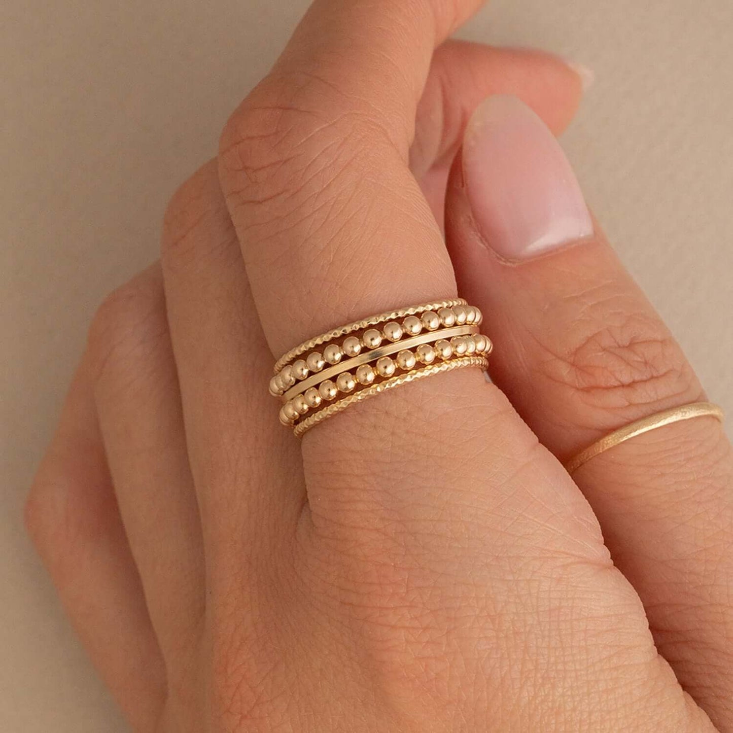 Gold ring on a finger against a neutral background