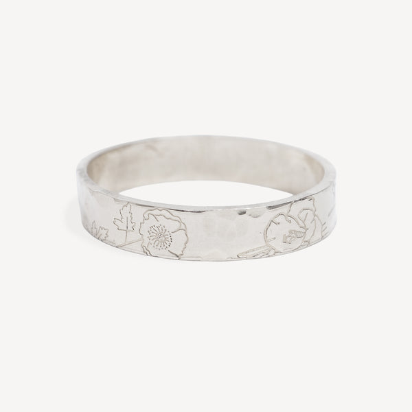 A silver band ring with a hammered texture and engraved floral patterns, shown on a light gray background.