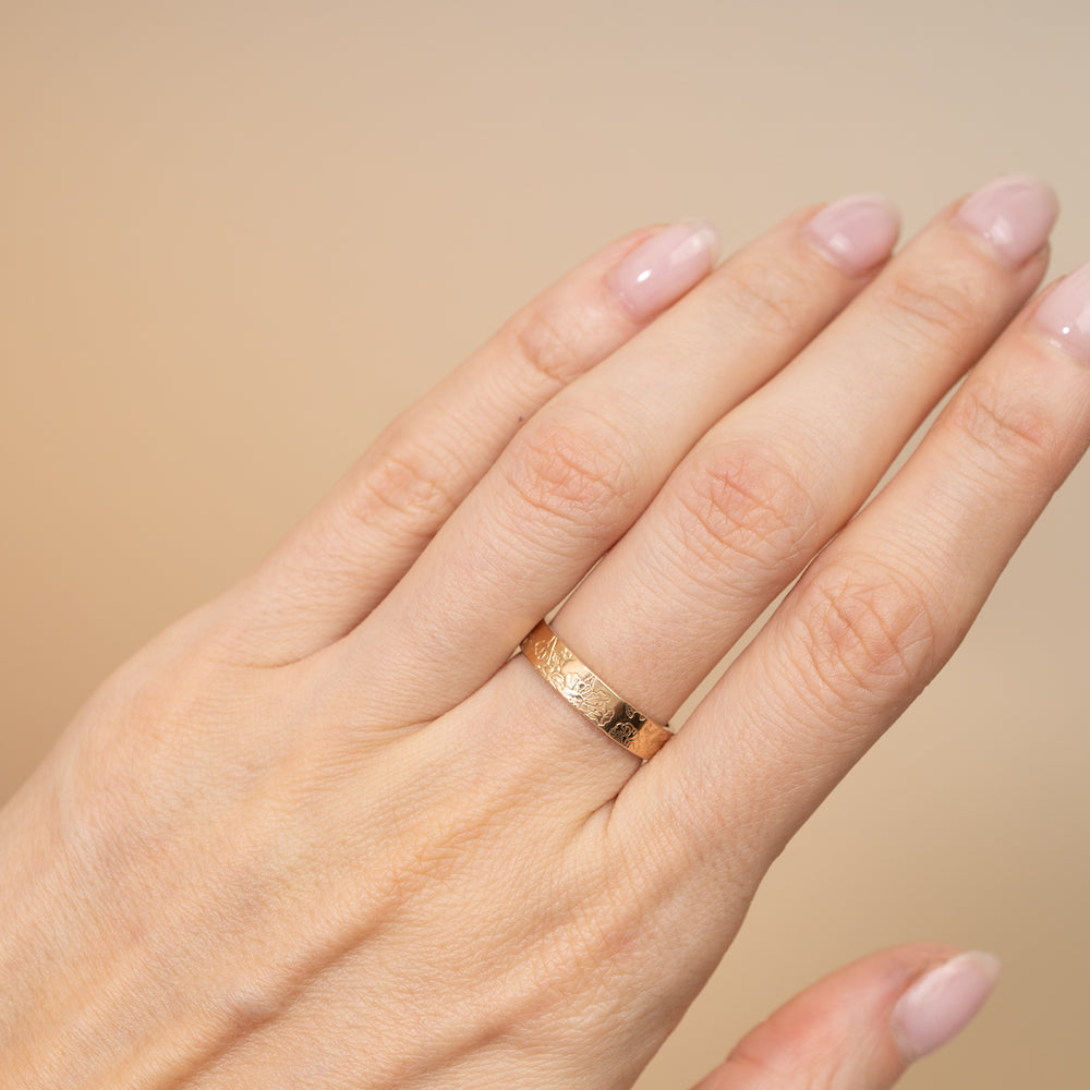Two engraved rings, one in polished yellow gold and one in silver, displayed overlapping on a clean off-white background.
